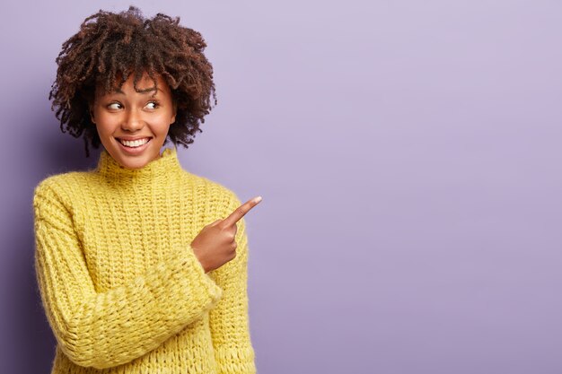 Młoda kobieta ma na sobie żółty sweter z fryzurą Afro