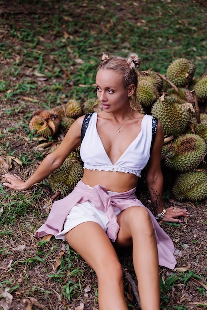 Młoda kobieta moda na tropikalnym polu z owocami duriana