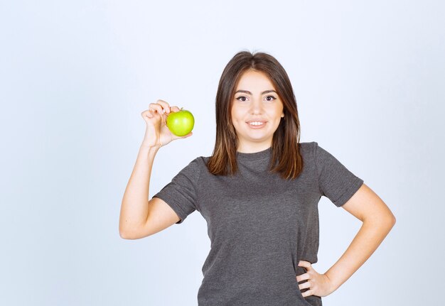 młoda kobieta model trzyma zielone jabłko.