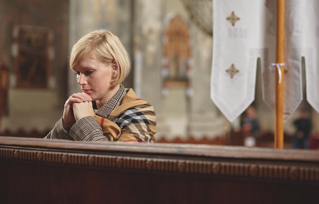 Młoda kobieta modli się w kościele.