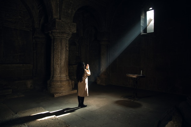 Młoda kobieta modlitwy w kościele ze światłem