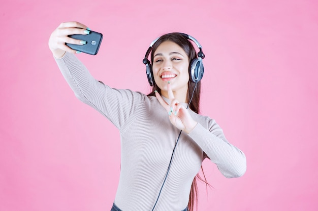 Młoda Kobieta Nosi Słuchawki I Biorąc Jej Selfie