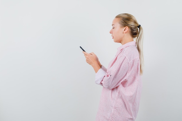 Młoda Kobieta O Czacie Tekstowym Na Telefon Komórkowy W Różowej Koszuli