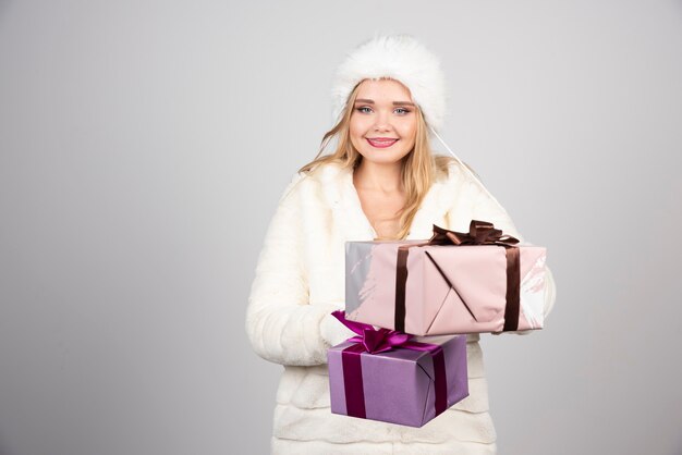 Młoda kobieta oferuje prezenty w zimowym stroju.
