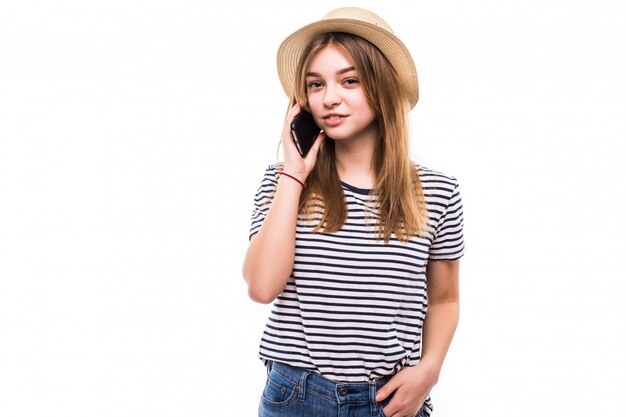 Młoda kobieta opowiada telefon odizolowywającego na biel ścianie