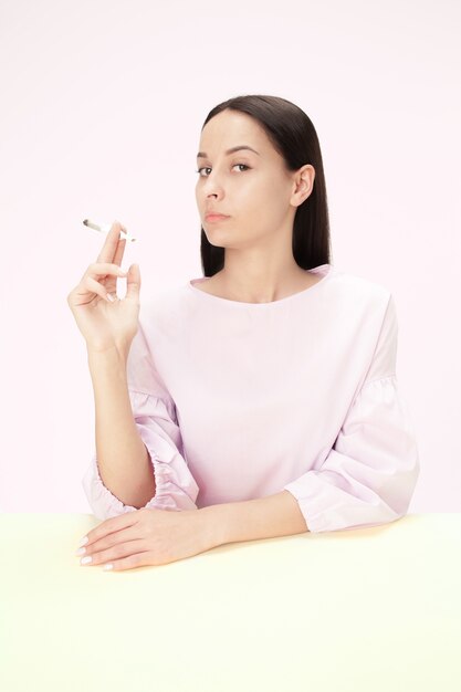 Młoda kobieta palenia papierosów siedząc przy stole w studio.