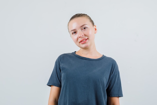 Młoda kobieta, patrząc w szary t-shirt i patrząc pozytywnie
