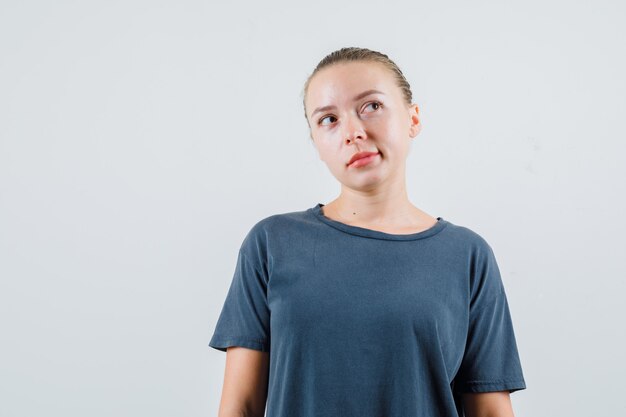 Młoda kobieta, patrząc w szary t-shirt i rozmarzona