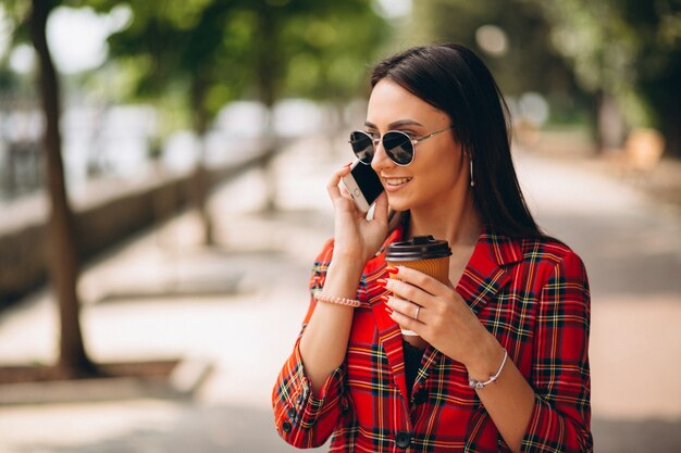 Młoda kobieta pije kawę i rozmawia przez telefon