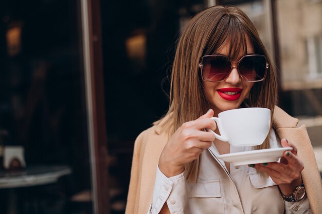 Młoda kobieta pije kawę w kawiarni na tarasie