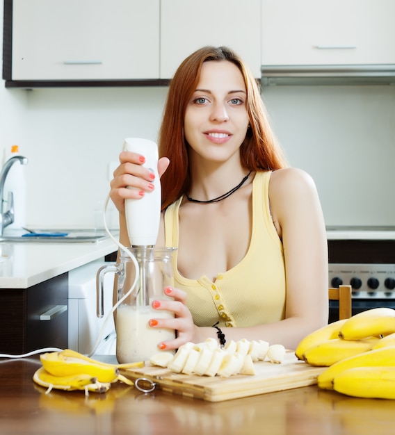 Młoda kobieta podejmowania napojów z blender z bananów