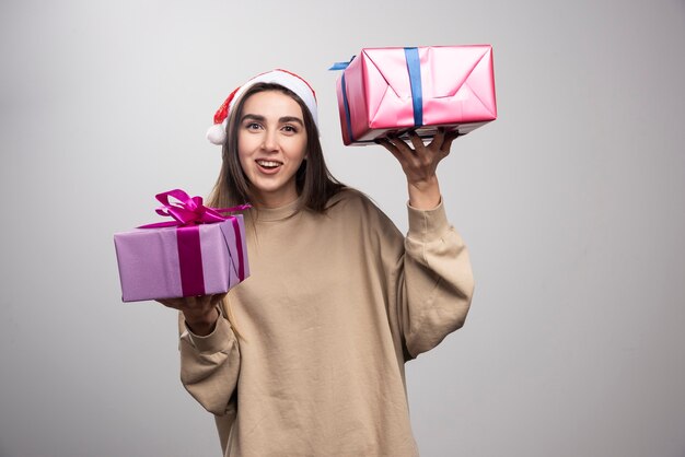 Młoda kobieta pokazuje dwa pudełka prezentów świątecznych.
