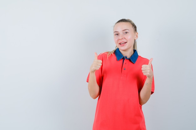 Młoda kobieta pokazuje podwójne kciuki w koszulce i wygląda wesoło