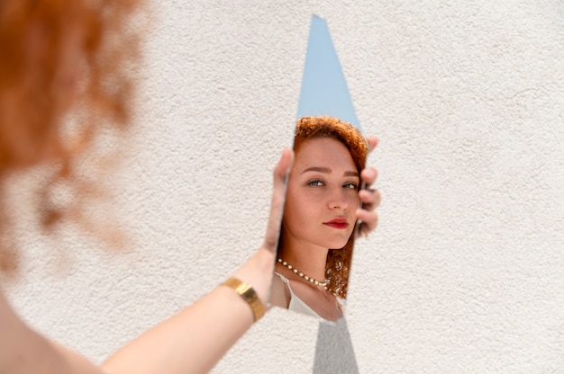 Bezpłatne zdjęcie młoda kobieta pozuje w odłamku lustra