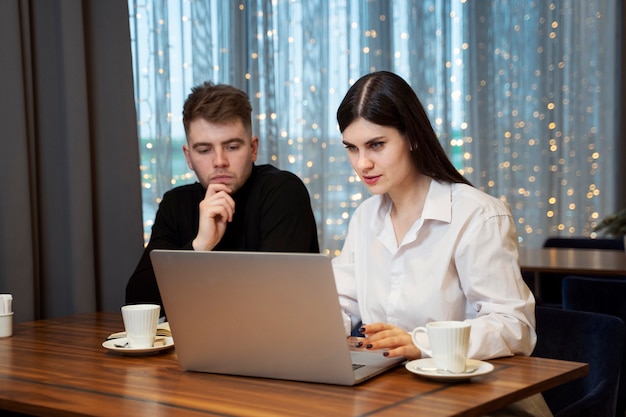 Młoda kobieta pracuje na swoim laptopie z kolegą w restauracji