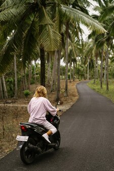 Młoda kobieta prowadząca motorower w tropikalnym życiu
