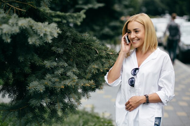 Bezpłatne zdjęcie młoda kobieta przy użyciu komputera przenośnego i inteligentnego telefonu. beautiful girl studenta pracy na laptopie na wolnym powietrzu