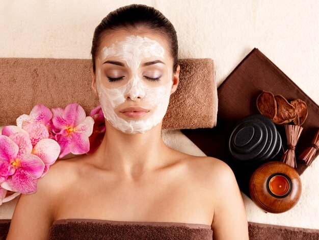 Młoda kobieta relaks z kosmetyczną maską na twarzy w salonie kosmetycznym w pomieszczeniu