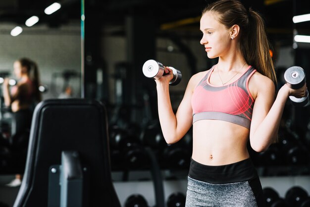 Młoda kobieta robi ćwiczeniom z dumbbells