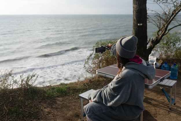 Młoda kobieta robi smartfonem zdjęcie krajobrazu morskiego
