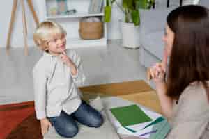 Bezpłatne zdjęcie młoda kobieta robi terapię mowy z małym blond chłopcem