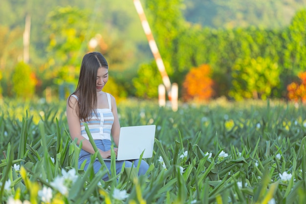Młoda kobieta robienia notatek w notatniku, siedząc w ogrodzie kwiatowym
