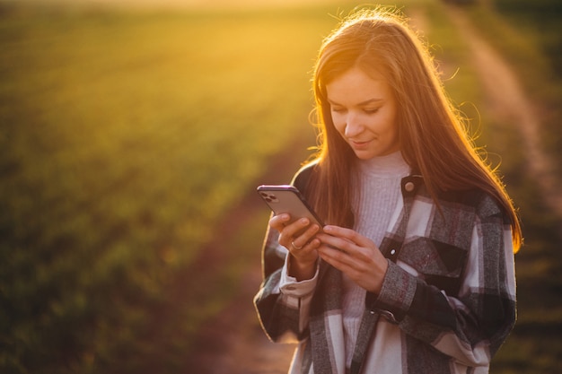 Młoda kobieta rozmawia przez telefon na zachód słońca