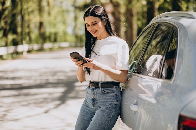 Młoda kobieta rozmawia przez telefon przez jej samochód elektryczny