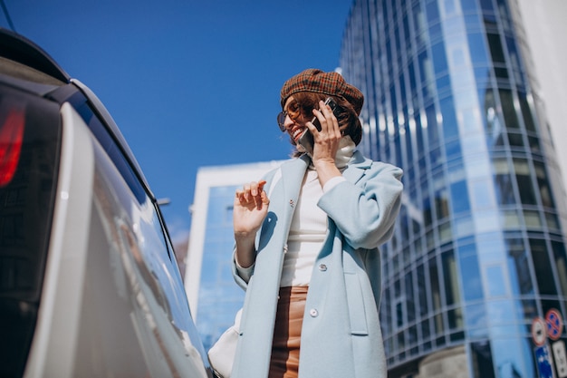 Młoda kobieta rozmawia przez telefon samochodem elektrycznym w centrum
