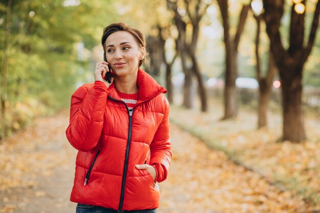 Młoda kobieta rozmawia przez telefon w jesiennym parku