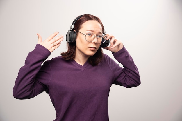 Młoda kobieta słucha muzykę w słuchawkach na bielu w szkłach. Zdjęcie wysokiej jakości