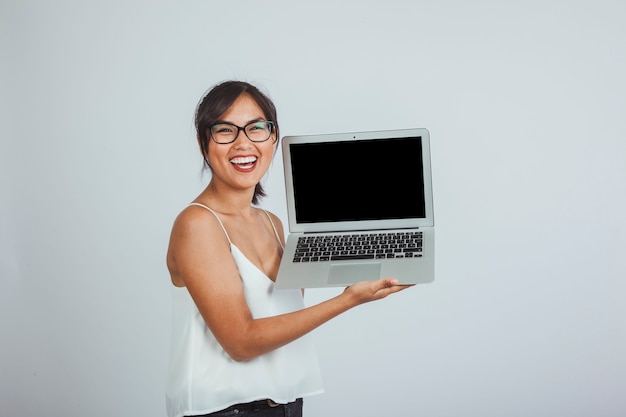 Młoda kobieta śmieje się i trzyma laptopa