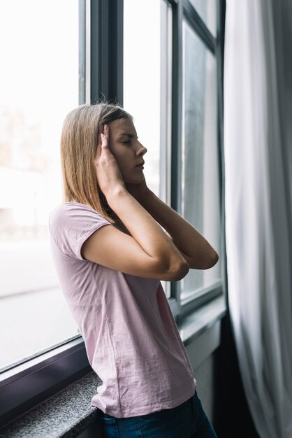 Młoda kobieta stoi blisko nadokiennego cierpienia od migreny