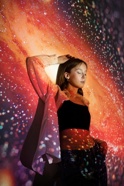 Bezpłatne zdjęcie młoda kobieta stojąca w projekcji tekstury wszechświata