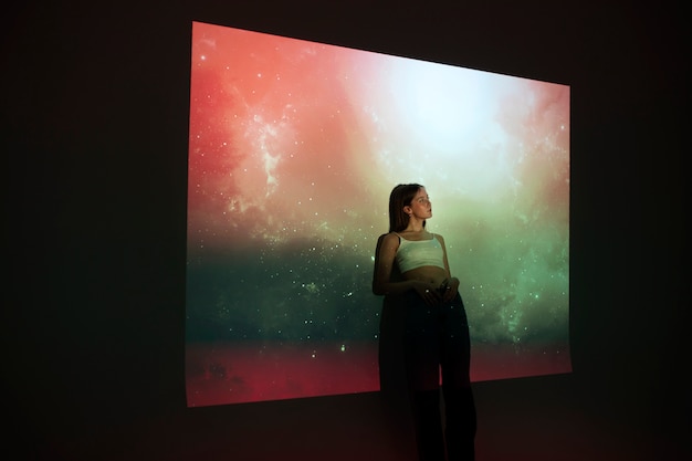 Bezpłatne zdjęcie młoda kobieta stojąca w projekcji tekstury wszechświata