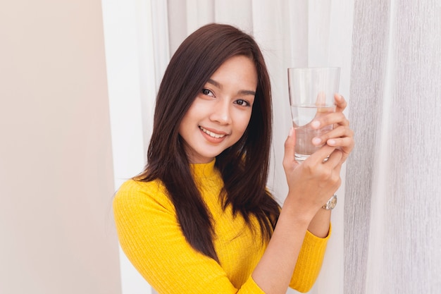 Bezpłatne zdjęcie młoda kobieta stwarzających ze szklanką wody
