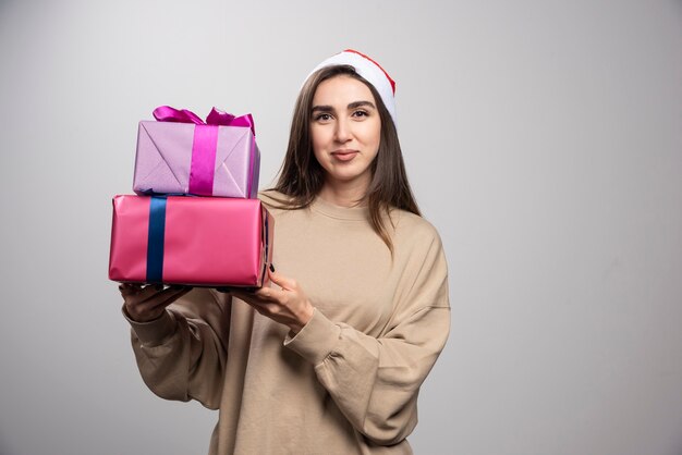 Młoda kobieta trzyma dwa pudełka prezentów świątecznych.