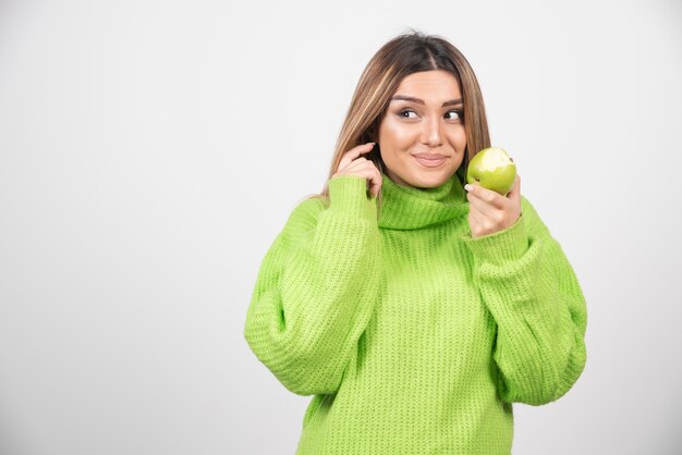 Młoda kobieta trzyma jabłko w zielonej koszulce