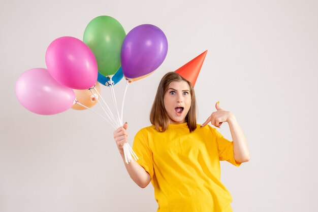 młoda kobieta trzyma kolorowe balony na białym tle