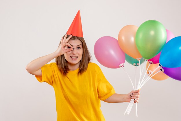 młoda kobieta trzyma kolorowe balony na białym tle