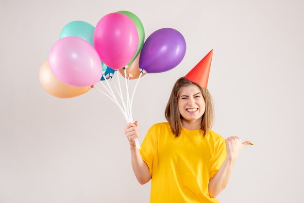 młoda kobieta trzyma kolorowe balony na białym tle