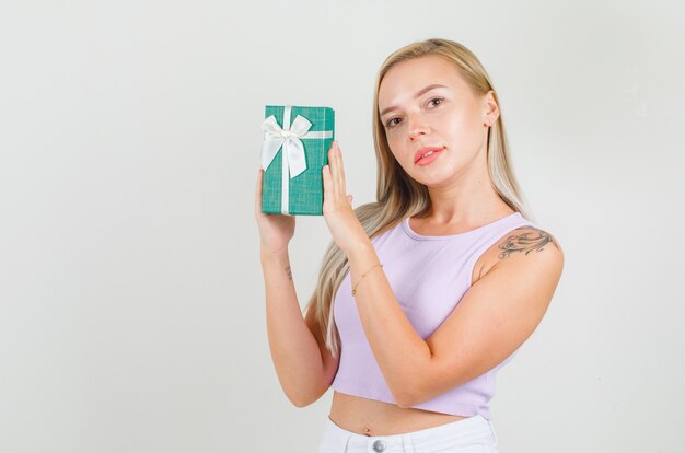 Młoda kobieta trzyma obecne pudełko w podkoszulku