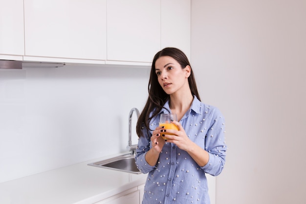 Młoda kobieta trzyma szkło sok pozycja w kuchni