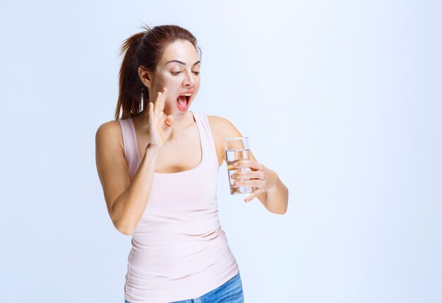 Młoda kobieta trzymająca szklankę wody i krzycząca
