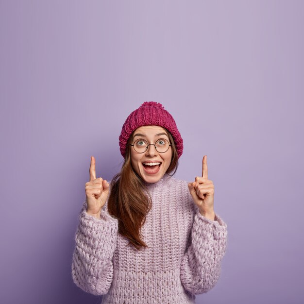 Młoda kobieta ubrana w fioletowy sweter i kapelusz