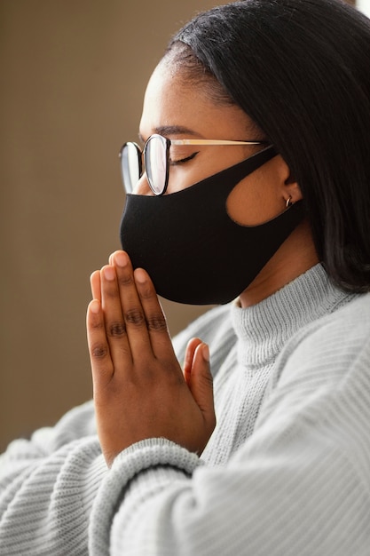 Bezpłatne zdjęcie młoda kobieta ubrana w maskę podczas modlitwy