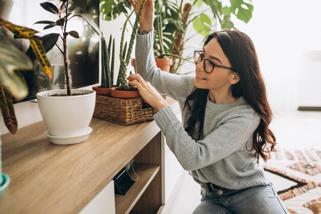 Młoda kobieta uprawia rośliny w domu