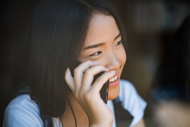 Młoda kobieta używa i patrzejący smartphone z czuć szczęśliwy