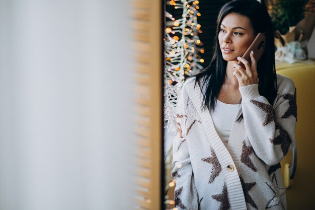 Młoda kobieta używa telefon i pozycję okno