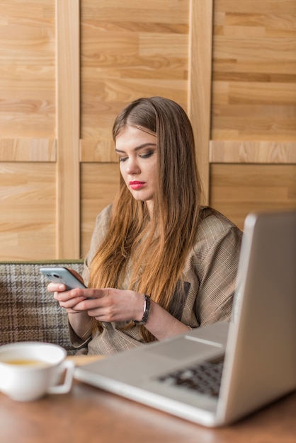 Młoda kobieta, używając jej telefon komórkowy w kawiarni